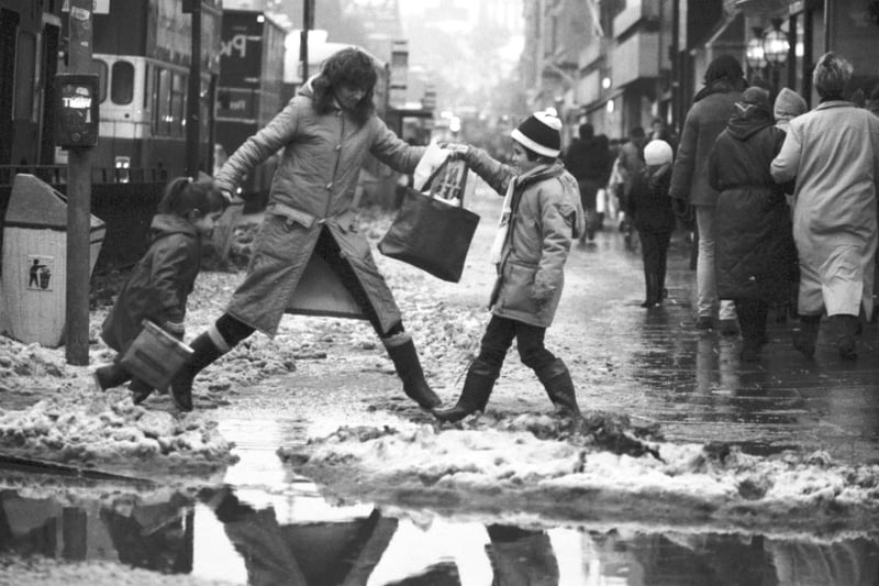 A woman jumps across a puddle and slush in Princes Street as the thaw begins after heavy snow hit Edinburgh in January 1987.