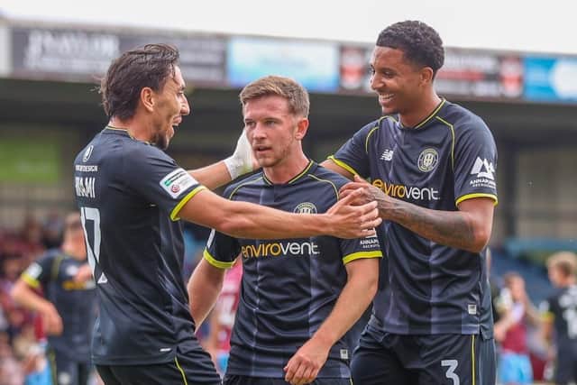 Will McGowan, centre, is congratulated by Josh Hmami and Ethan Bristow after firing Harrogate Town into a 14th-minute lead at Scunthorpe United. Picture: Matt Kirkham