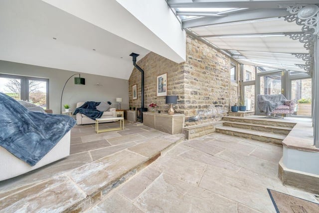 A snug with a cosy stove, and exposed stone wall leads in tot he conservatory.