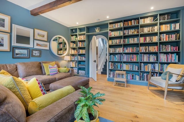 A spacious sitting room has an arched doorway and shelving to one wall.