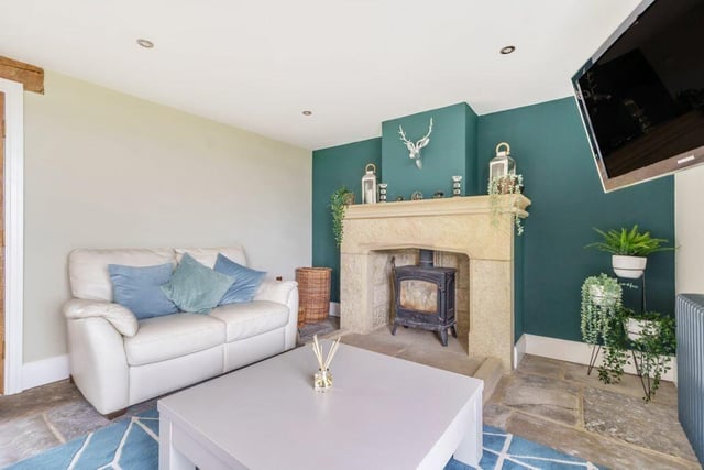 A stone fireplace and log burner is a feature in the sitting and dining room.