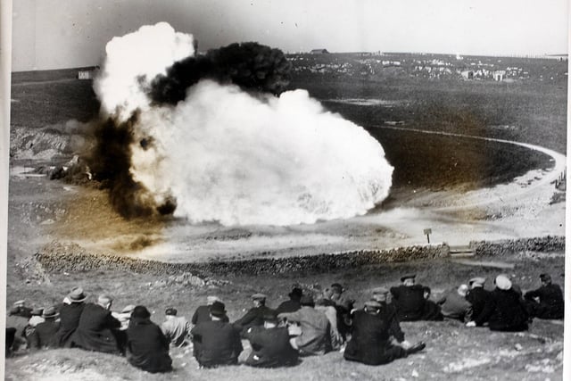 300 Durham miners watching a controlled explosion at the Mines Research Station at Harpur Hill, Buxton, Derbyshire. The explosion was specially staged using underground coal dust - the flame which shot out of a tunnel was 300 feet long, and made an impressive picture.
