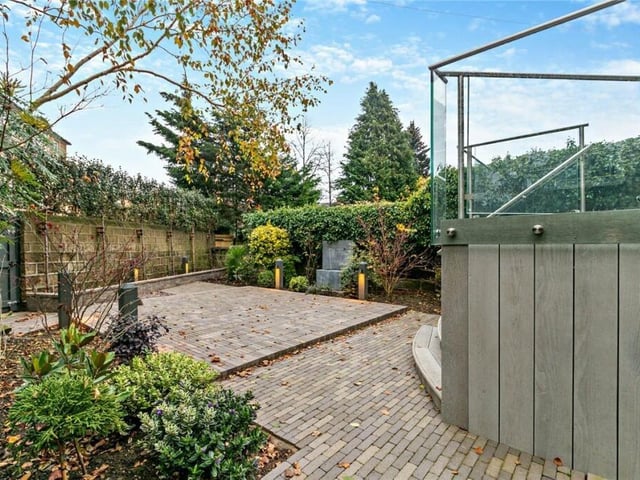 An enclosed garden has a raised terrace and a sunken patio with water feature.