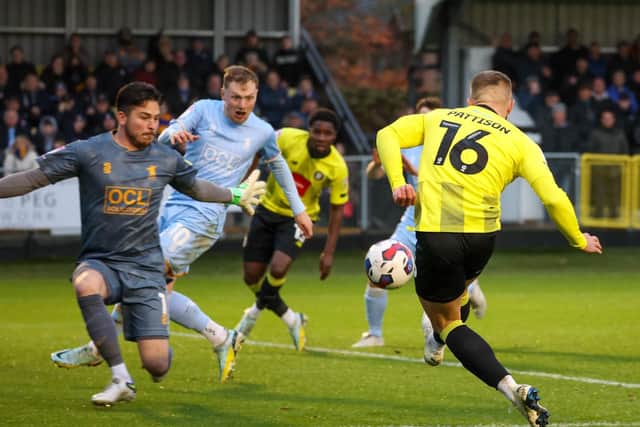 Alex Pattison beats Mansfield Town goalkeeper Christy Pym to set Harrogate Town on their way to a 3-0 success at Wetherby Road.