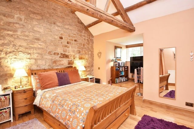 A double bedroom with vaulted and beamed ceiling, and feature stone wall.
