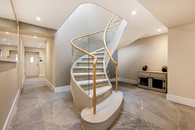 A modern winding staircase leads up from the hallway to the first floor.