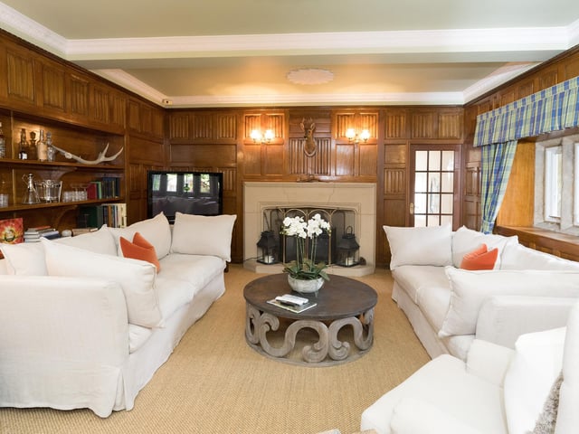 An impressive reception room with feature fireplace and wood panelling to the walls.