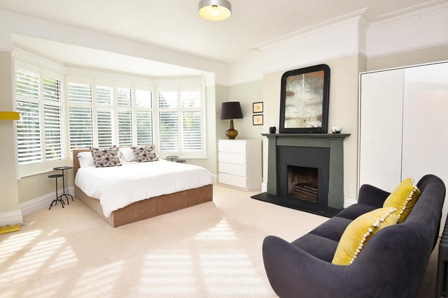 A light and spacious bay-fronted bedroom has a feature fireplace.