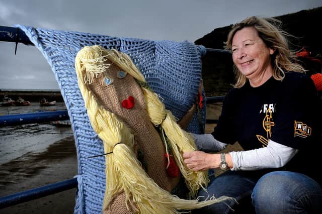 Jacqueline Power arranges the knitted Mermaid on the seafront in Staithes