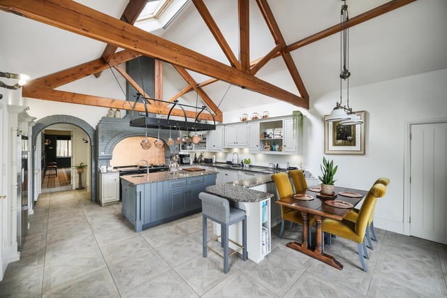 The stylish kitchen with a vaulted ceiling, an Aga, and brick chimney feature above the stove.