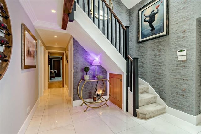A sleek and modern hallway with a staircase leading up. A second staircase to the first floor is from a sitting room.