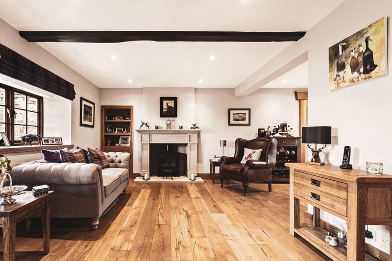 The house opens to an exceptionally large reception room with solid strip oak flooring and a feature fireplace with a log burning stove.