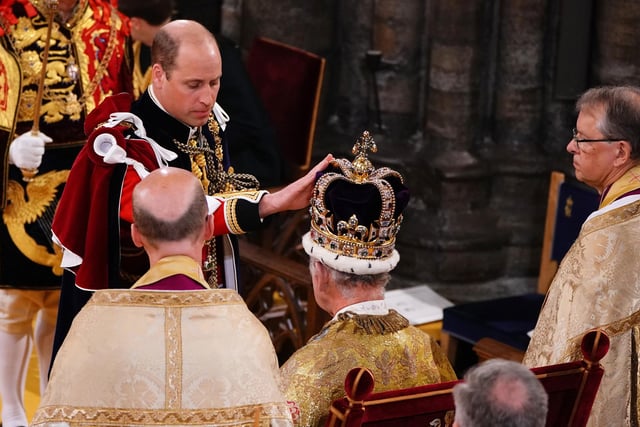 Prince William, Prince of Wales touches the St Edward's Crown his father's, King Charles III during the King's Coronation Ceremony.