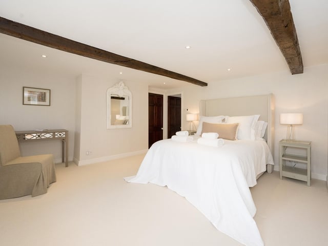 A large double bedroom with beams to the ceiling.