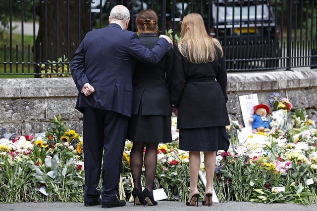 Prince Andrew, Duke of York puts his arm around Princess Eugenie of York and Princess Beatrice of York as they look at floral tributes outside Crathie Kirk church. (Photo by Jeff J Mitchell/Getty Images)