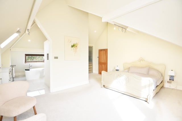 This stunning bedroom is open plan to its en suite, with a free standing bath beneath a Velux window.