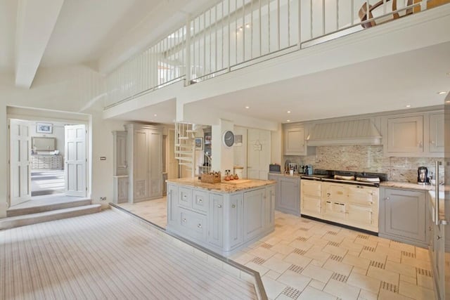 The stylish kitchen with bespoke units and granite worktops has an Aga and a central island.