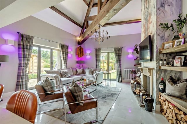 Relaxing space with a vaulted roof, fireplace containing a wood burning stove, and bi-fold doors to the gardens.