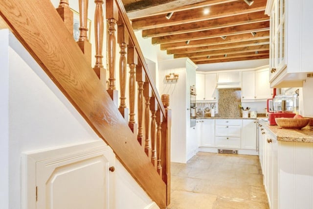The kitchen area is bright and extends down the hall to a staircase.