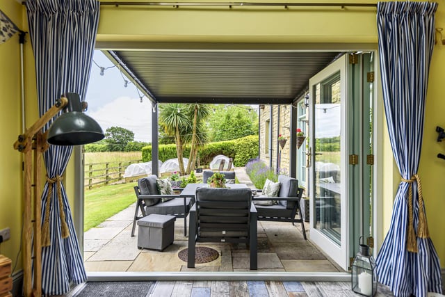Bi-fold doors open to an outdoor sitting and dining area that is perfect for entertaining purposes.
