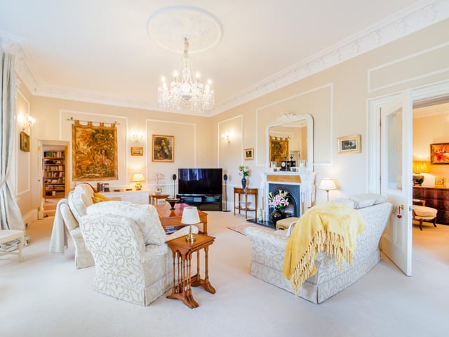 An elegant reception room with central fireplace and a front bay window.