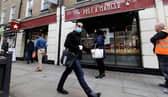 A man wearing PPE (personal protective equipment) passes customers queuing to enter a recently re-opened Pret-A-Manger shop which had originally closed-down due to the COVID-19 pandemic in London (Photo: TOLGA AKMEN/AFP via Getty Images)