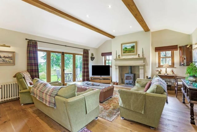 This sitting room with lfeature fireplace and log burner, has doors leading out to the garden terrace.