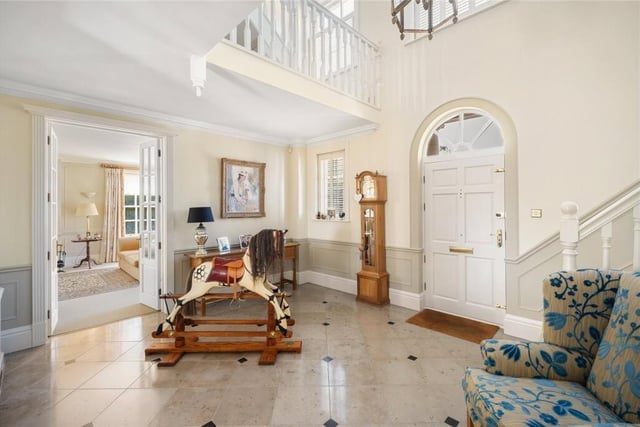 The entrance hall has a polished limestone floor, and a turned staircase to a gallery landing.