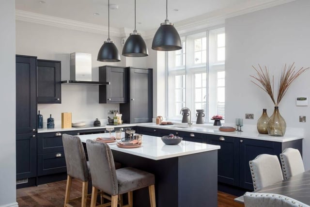 The stylish kitchen has bespoke shaker-style units and a central island with breakfast bar.