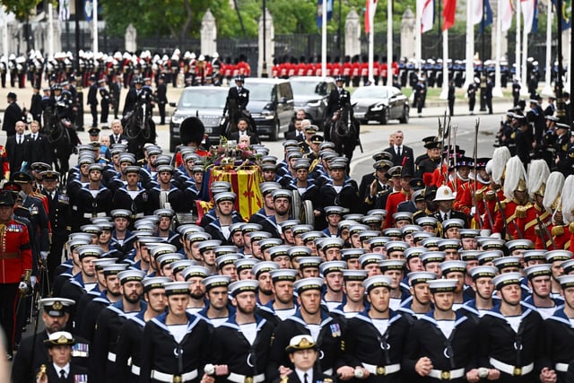 Royal Navy saliors take the coffin of Queen Elizabeth II, draped in a Royal Standard and adorned with the Imperial State Crown and the Sovereign's orb and sceptre on the State Gun Carriage of the Royal Navy to Westminster Abbey for the State Funeral Service for Britain's Queen Elizabeth II. (Photo by Oli SCARFF / AFP) (Photo by OLI SCARFF/AFP via Getty Images)