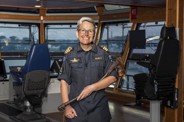 Commander Yvonne Gray from Harrogate stands of the bridge of HMNZS Manawanui. She is holding a Maori ceremonial adze, a toki poutangata.