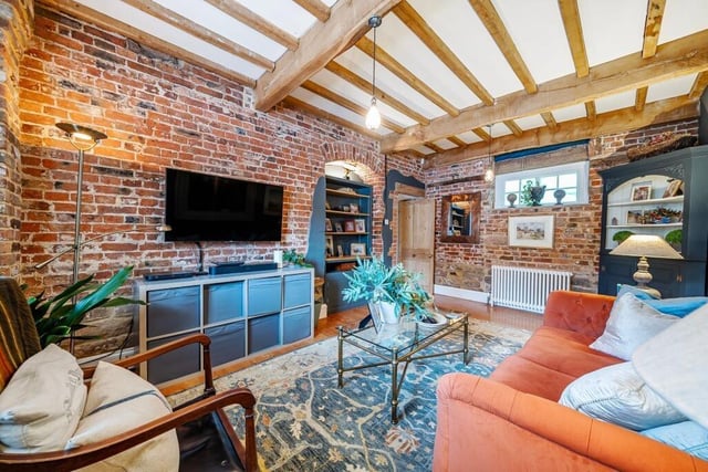 A beamed living room, with exposed brick feature walls.