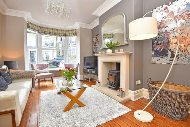 Light pours in to the sitting room through a large bay window, and a feature fireplace holds a woodburner stove.