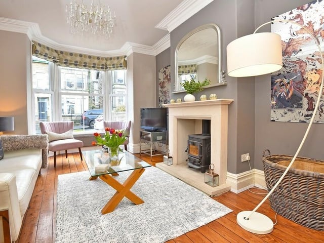 Light pours in to the sitting room through a large bay window, and a feature fireplace holds a woodburner stove.