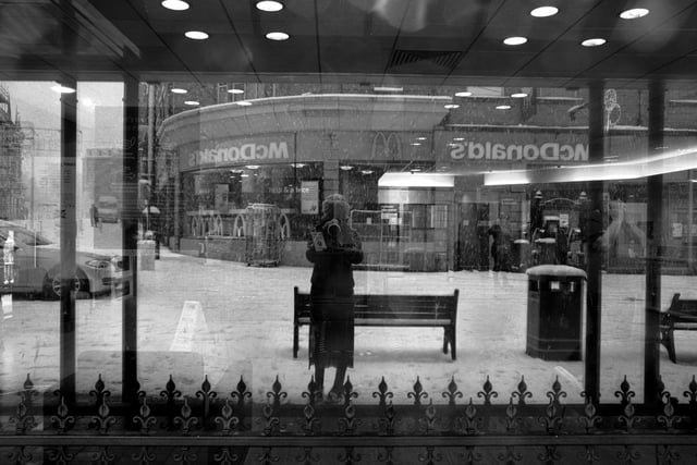 The image was taken on Cambridge Road through an empty shop window reflecting McDonald's in the background.