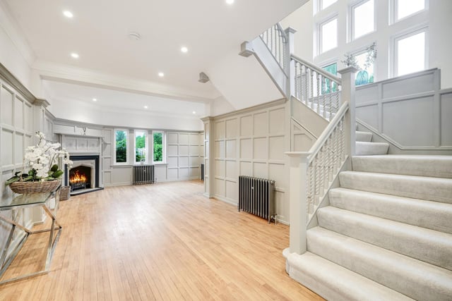 The hallway with its solid oak floor, wall panelling, open fire and staircase up.