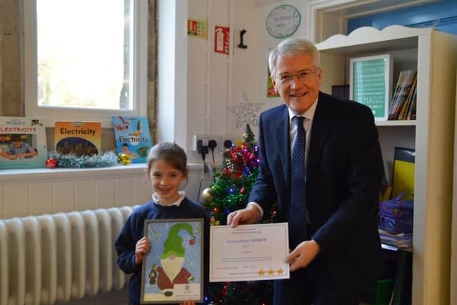 Harrogate and Knaresborough MP Andrew Jones presenting Izzy Smith with a framed copy of her card design. (Picture contributed)