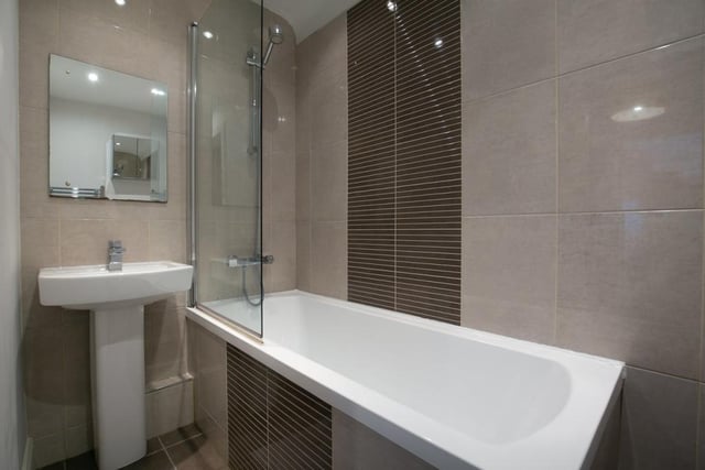The stylish bathroom is fitted with a three-piece suite, mains mixer shower over the bath, tiled flooring and splash walls.