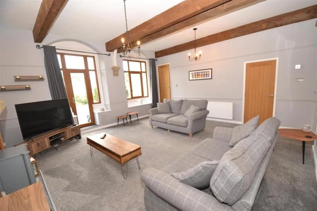 A spacious living room with glass panel door and windows allowing light to flood in.