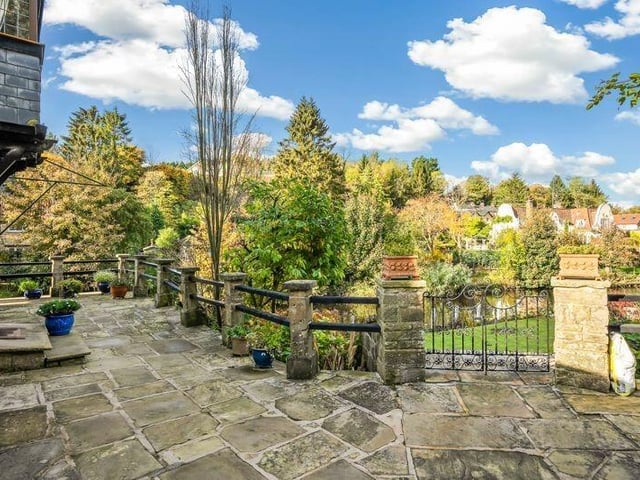 A stone terrace has steps leading down to a lawned garden.
