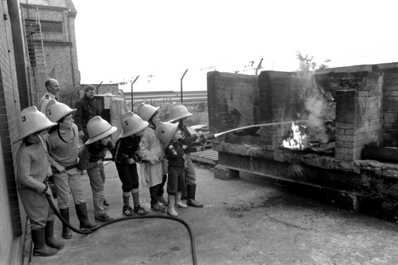 Small boys from the 68th Salisbury Cub Scout pack, wearing firemen's helmets, put out a fire on a visit to McDonald Road fire station in Edinburgh June 1987.