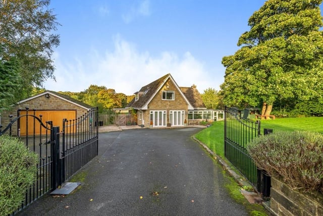 Wrought iron gates open to the driveway of the property, with parking space and a garage to the left.