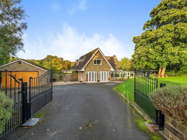 Wrought iron gates open to the driveway of the property, with parking space and a garage to the left.
