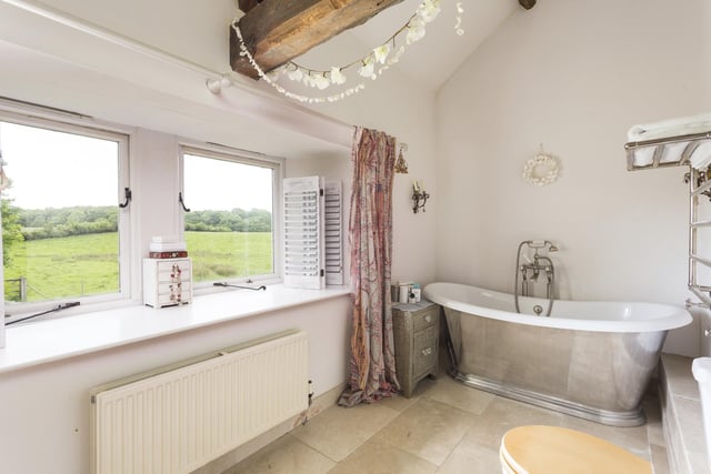 A deep, free standing bath tub features in this house bathroom with a rural outlook.