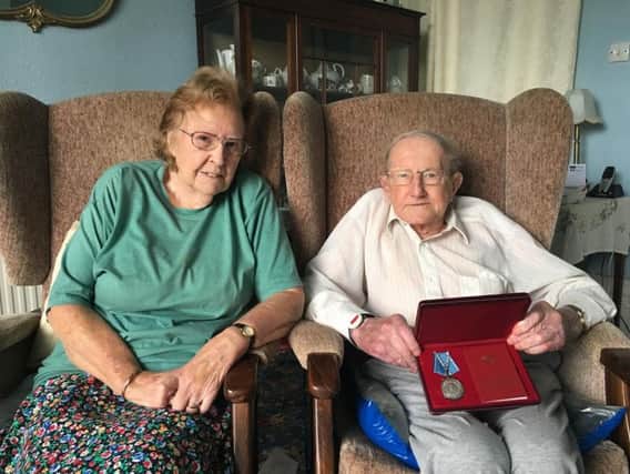 Dennis at home with his wife Freda, holds up his Ushakov medal proudly