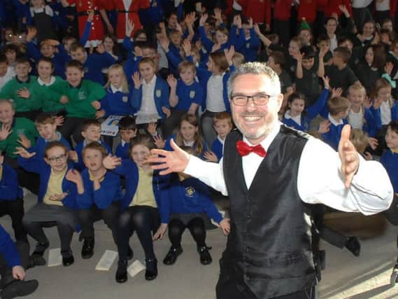Organiser of the concert and conductor, Andrew Roberts, with a crowd of the children who performed in the concert.