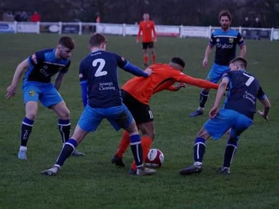 A trio of Tadcaster Albion players attempt to take the ball off a Brighouse attacker