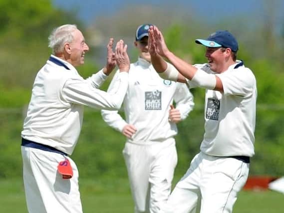 Experienced Masham bowler Derek Chapman, left, is congratulated after taking the first of his four wickets against West Tanfield. Picture: Gerard Binks