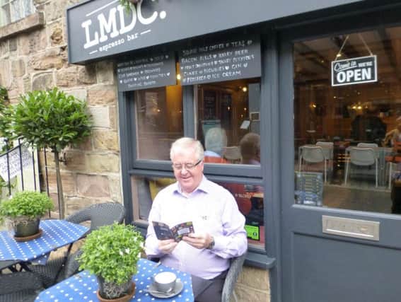 Harrogate BID chairman John Fox leafs through the ha ndy new guide outside independent Harrogate cafe LMDC.