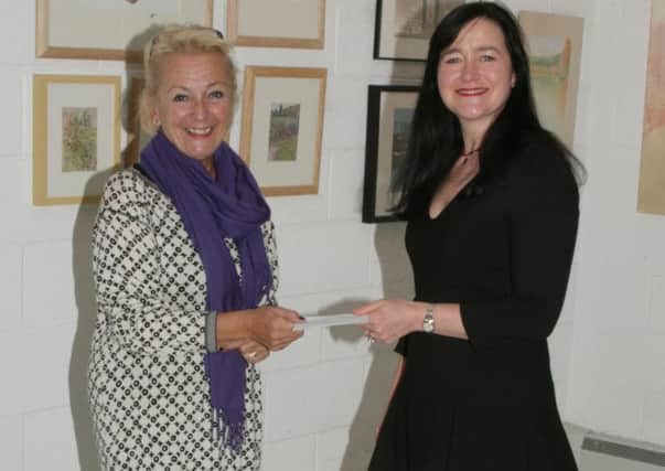 Annette Petchey, CEO of New Light, right, receives the donation from Marilynne Jackson (left) of SAL.